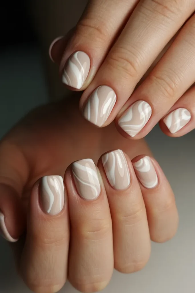 Short square nails with beige and white swirl patterns.