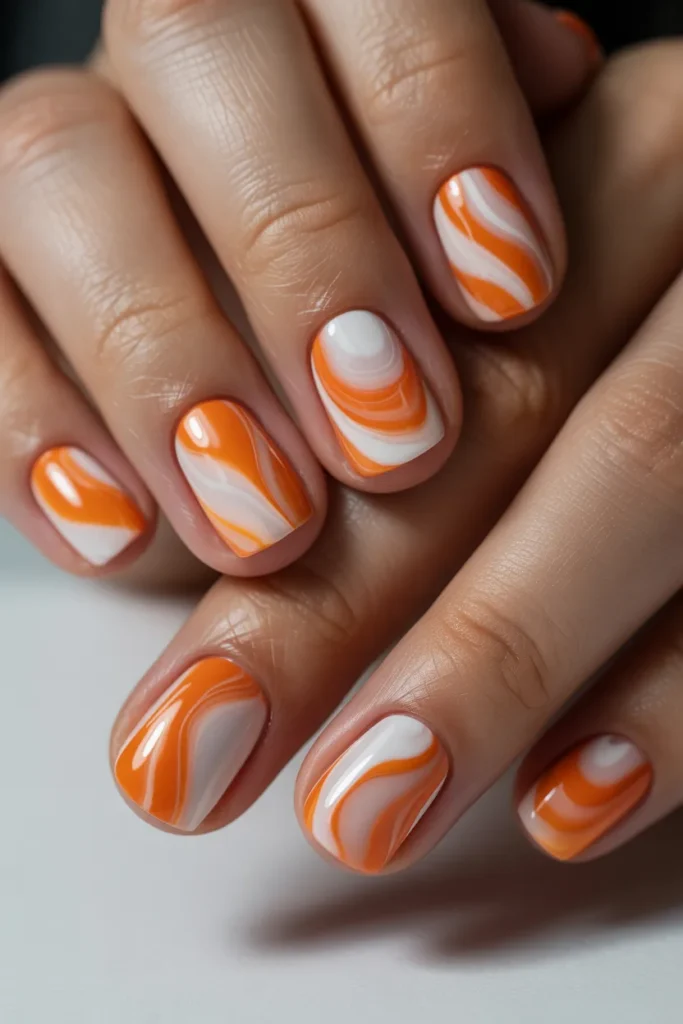 Swirled orange and white marble nail design
