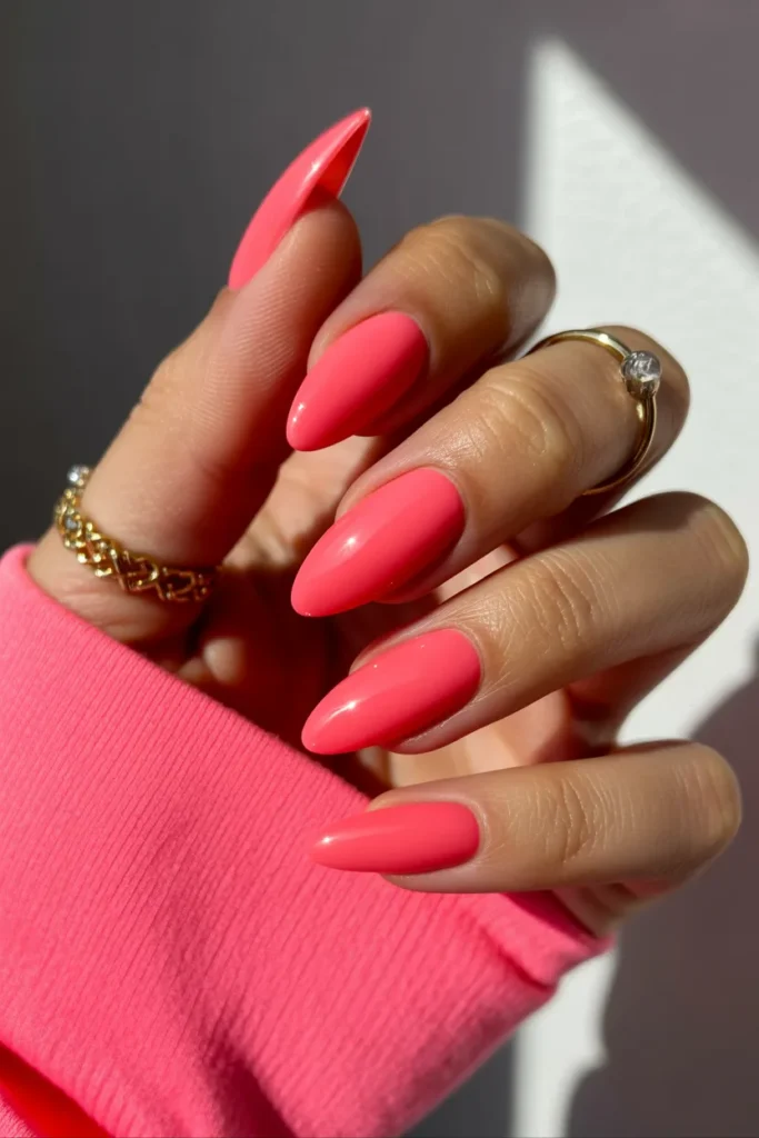 glossy neon pink almond-shaped nails in bright sunlight